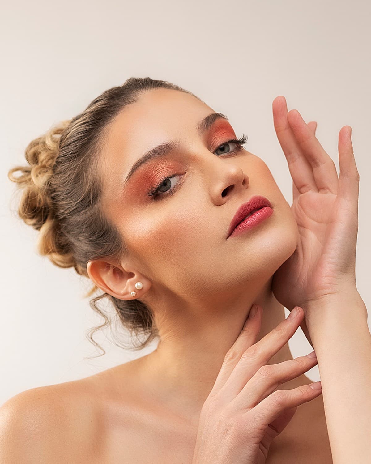 Retrato de beauty con maquillaje colorido, manos enmarcando el rostro
