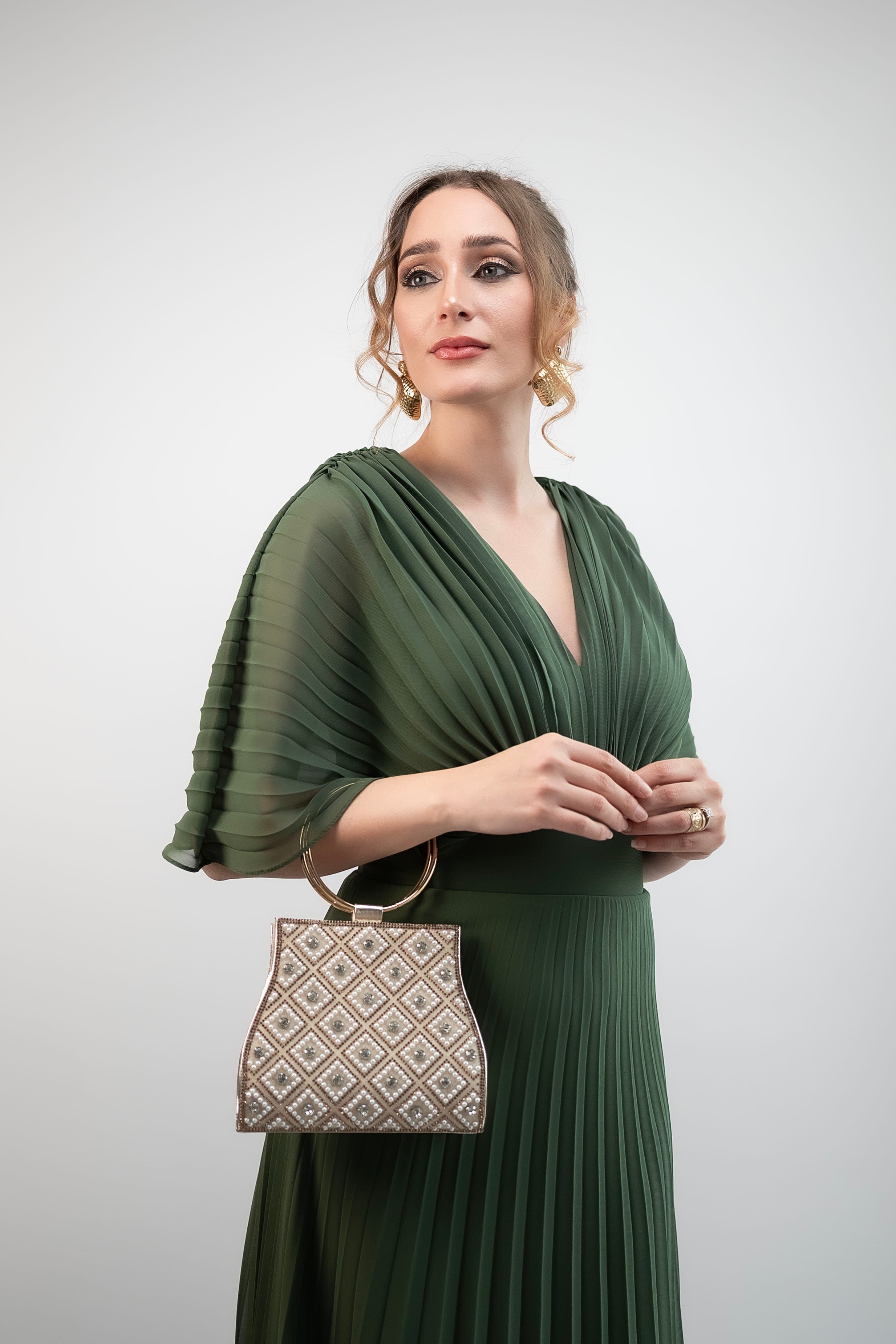 Retrato editorial con vestido verde esmeralda, pose de cuerpo completo sobre fondo neutro