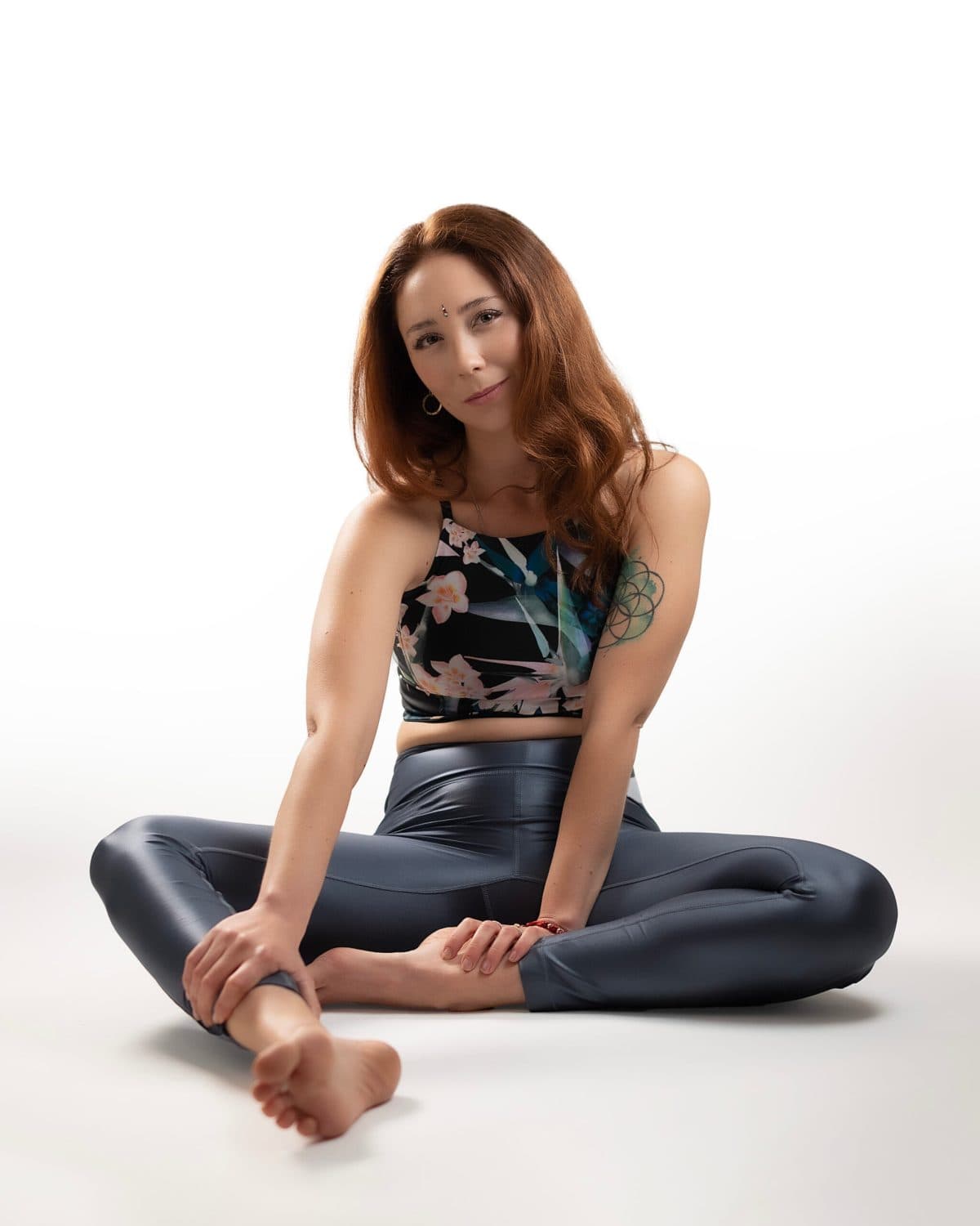 Retrato de yoga a color, sentada sonriente apoyada en un mat enrollado