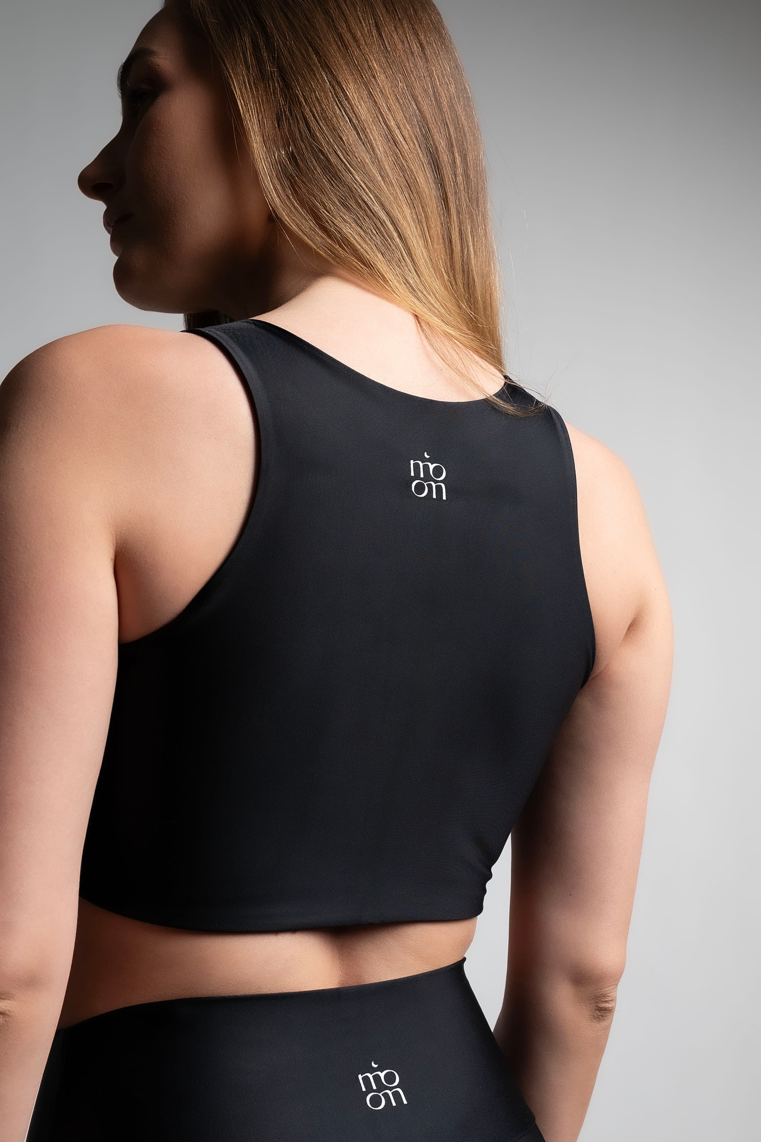 Fotografía comercial de ropa deportiva, conjunto negro, vista de espalda sobre fondo de estudio