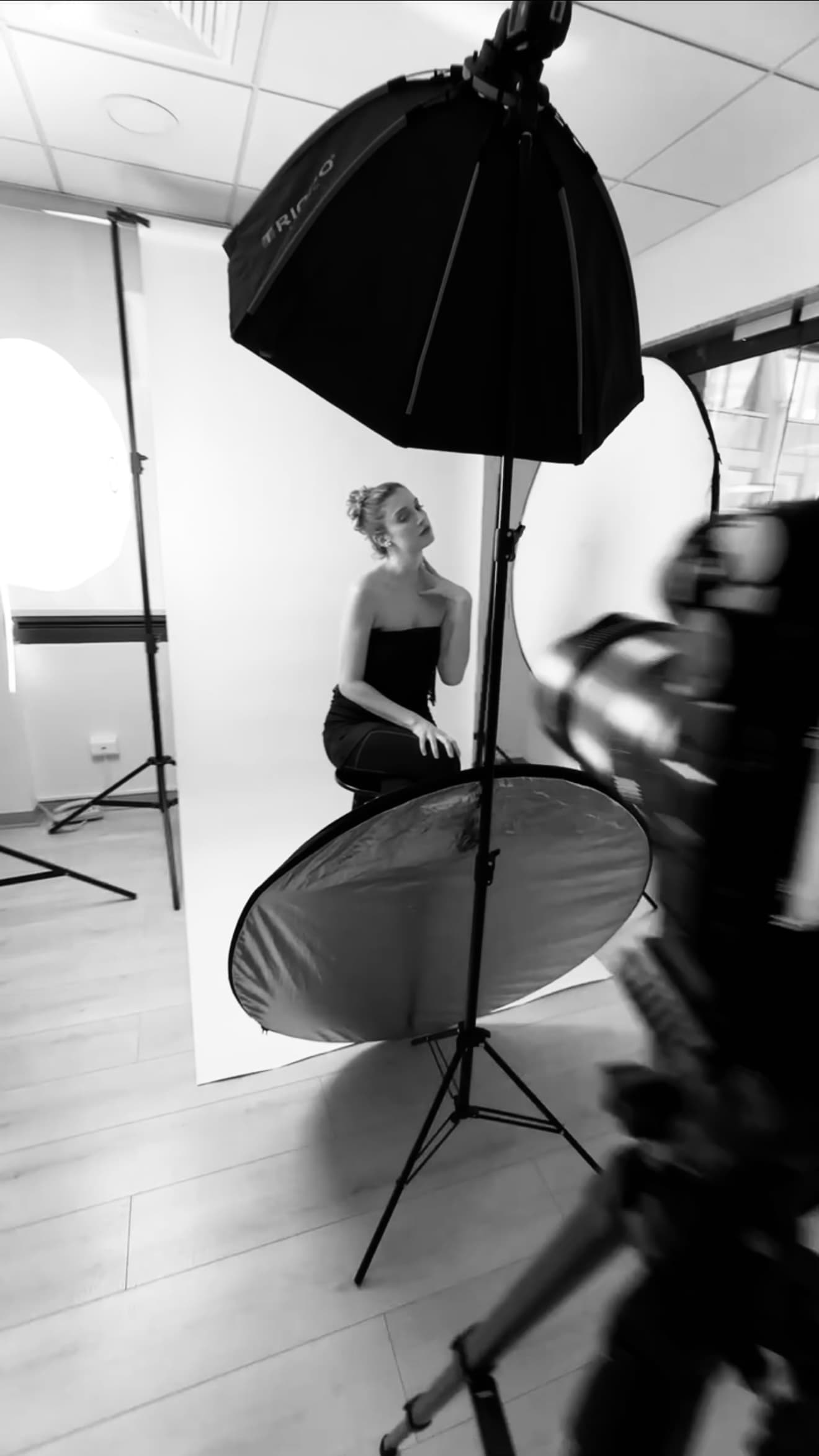 Sesión de estudio en curso, con softbox y reflector armados alrededor de la modelo