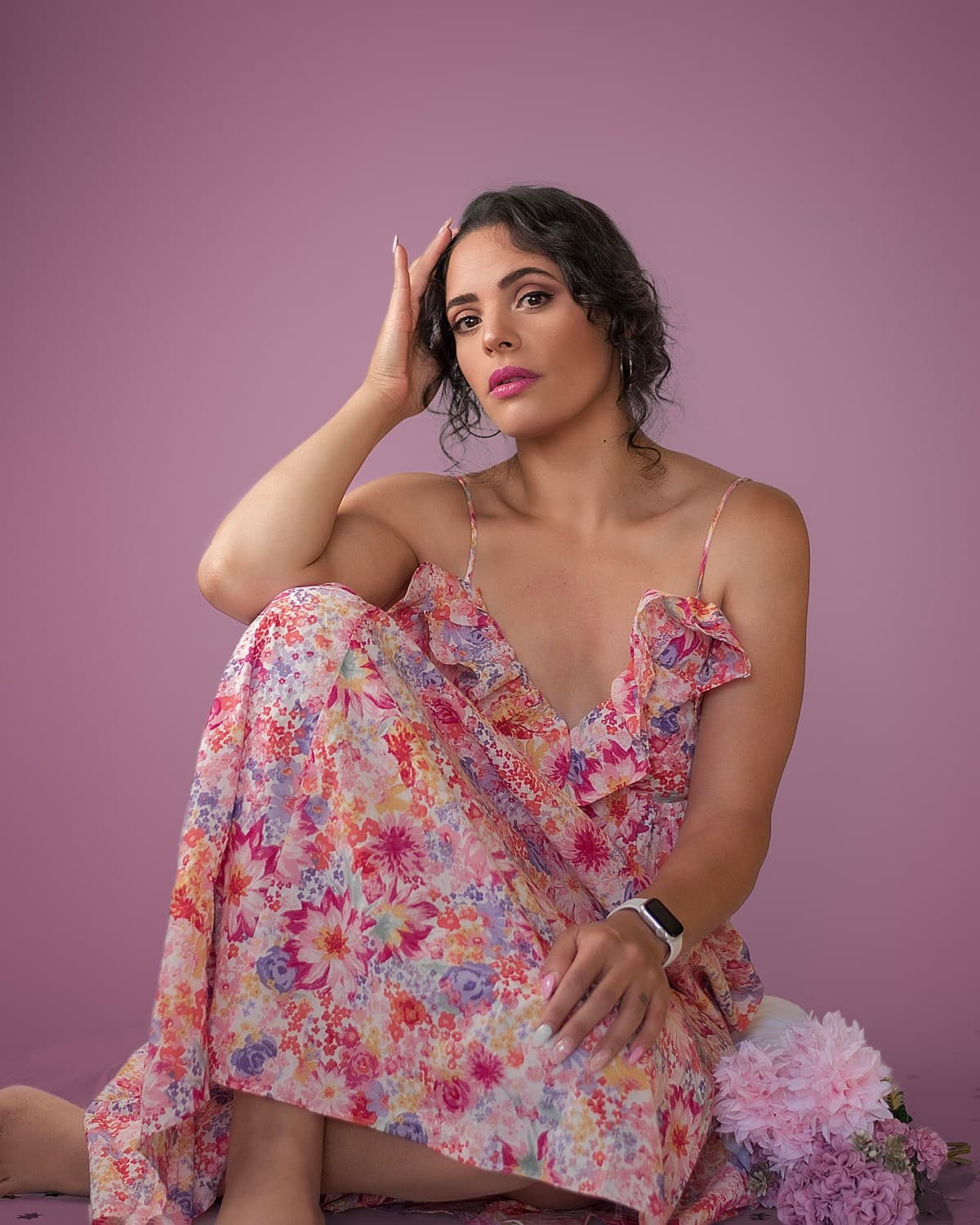 Retrato editorial con vestido floral, mano cerca del rostro sobre fondo magenta