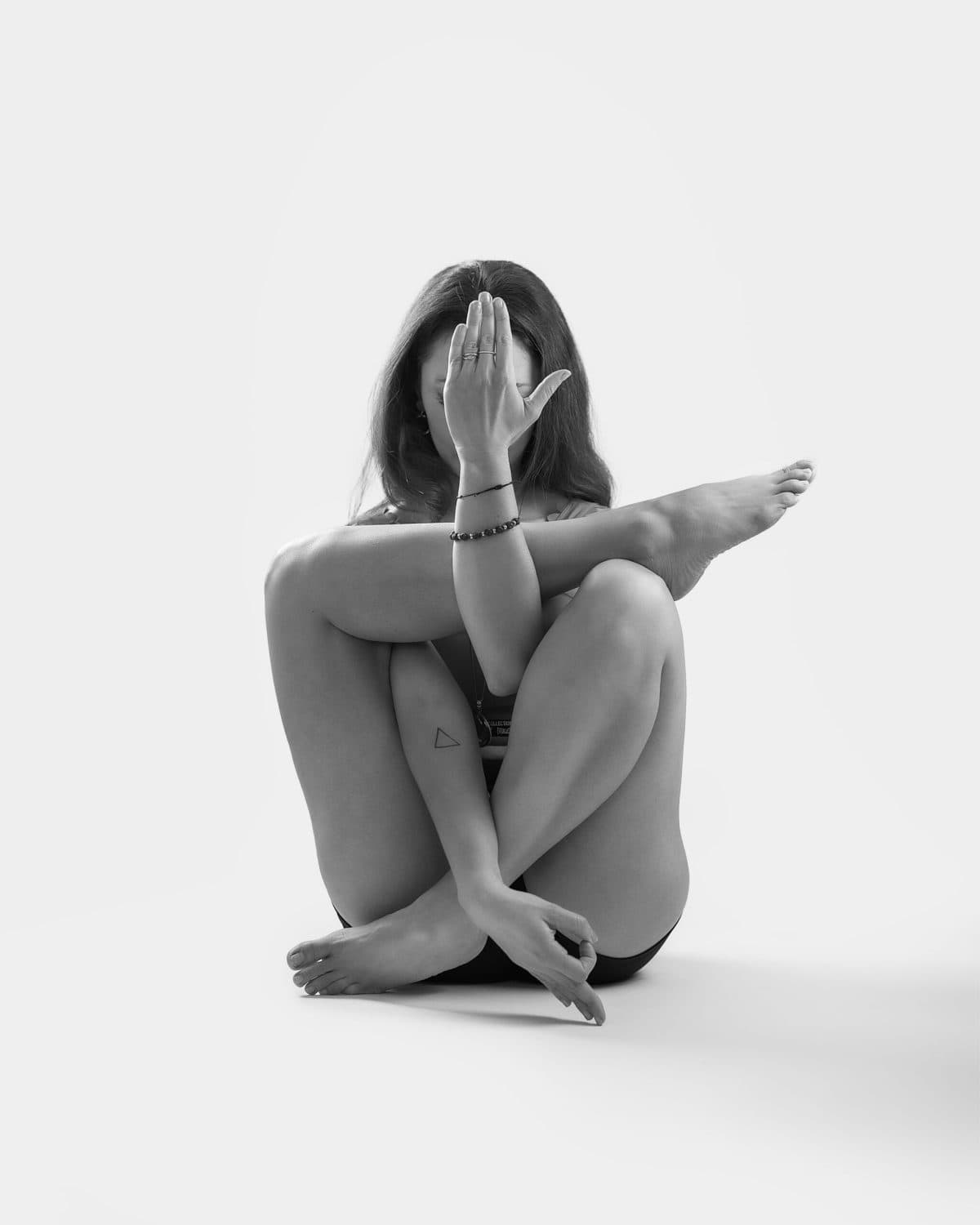 Retrato artístico en blanco y negro, sentada con brazo cubriendo parcialmente el rostro